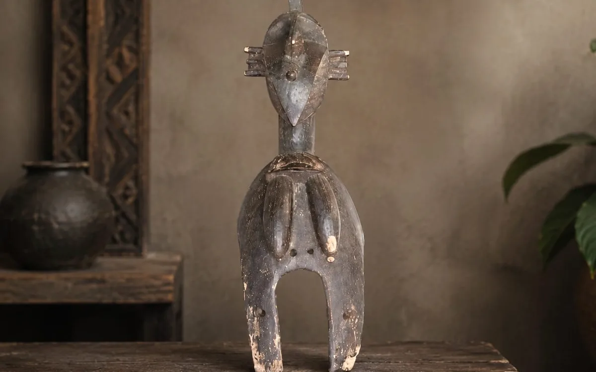 Statuette protectrice en bois sombre posée sur une table ancienne