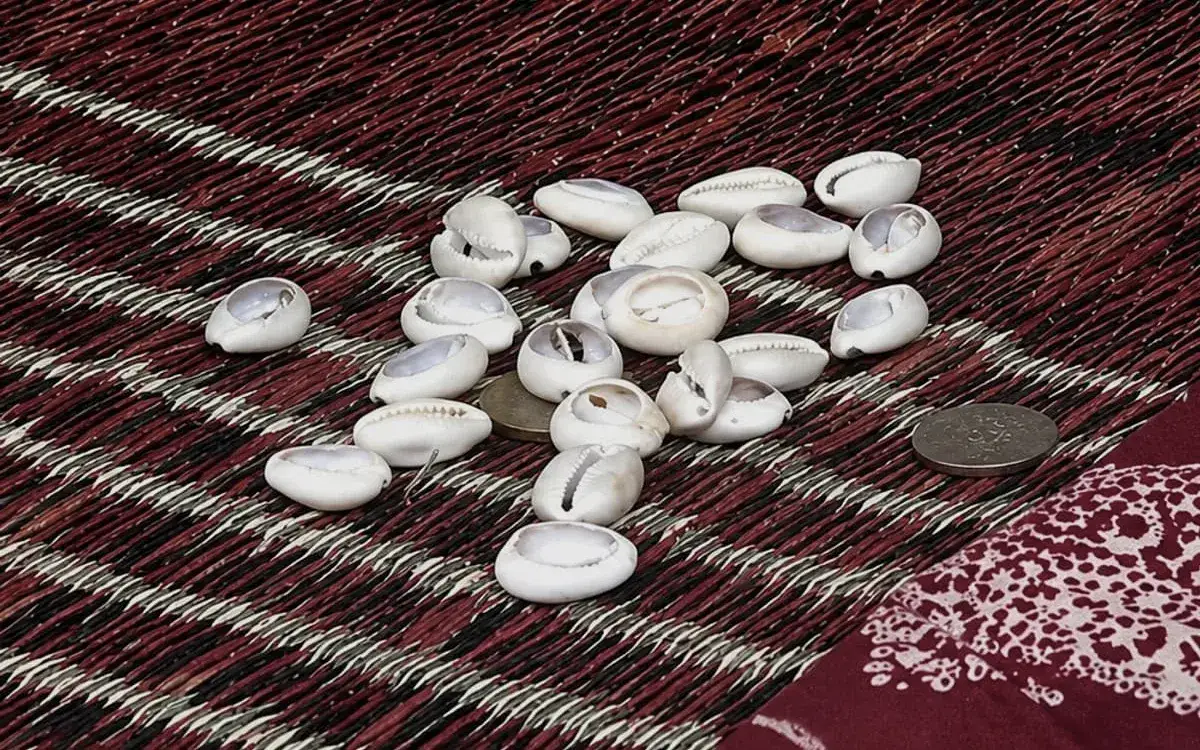 Cauris blancs jetés sur une natte tissée